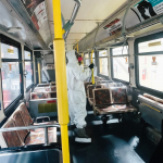 Person wearing hazmat suit inside an empty transportation bus