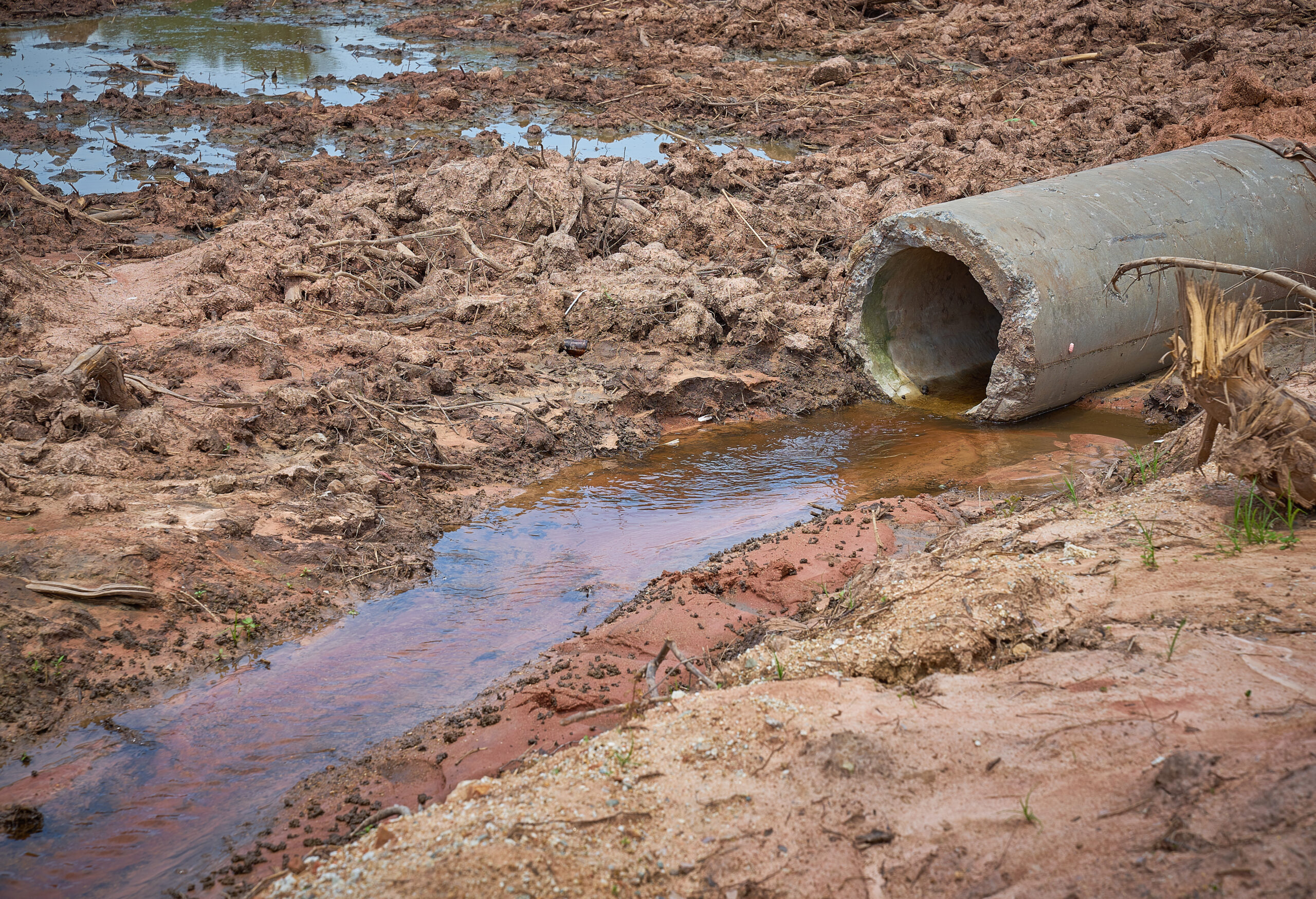 Waste water flowing onto the land from broken cement draining pipeline causing contamination.